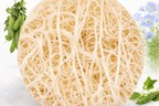 Round loofah with natural fibers on a white background with greenery