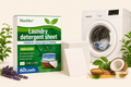 Maebho laundry detergent sheet packaging with a washing machine and laundry items on a light background