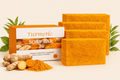 Turmeric soap bars with packaging and turmeric roots on a light background