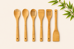 Set of wooden kitchen utensils on a light background with green leaves.