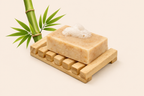 Bar of soap on a wooden soap dish with bamboo leaves on a beige background