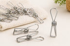 Metal clothespins on a white surface with a towel and plant in the background