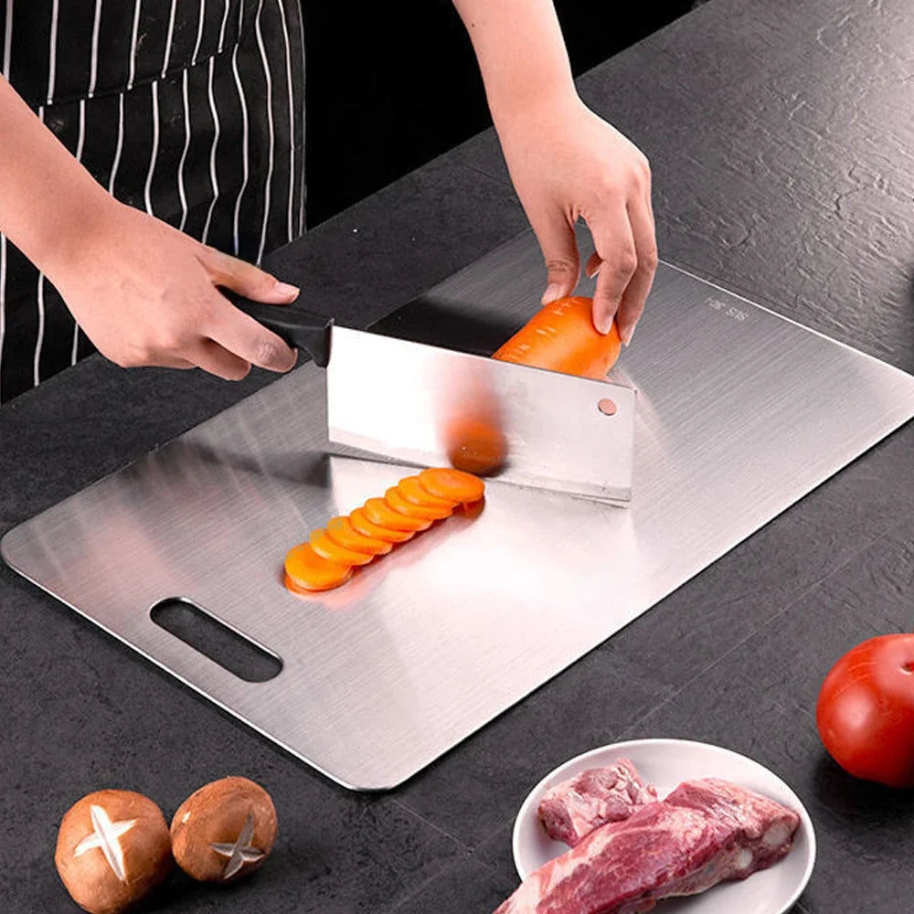 Person slicing carrots on a stainless steel cutting board with a knife.